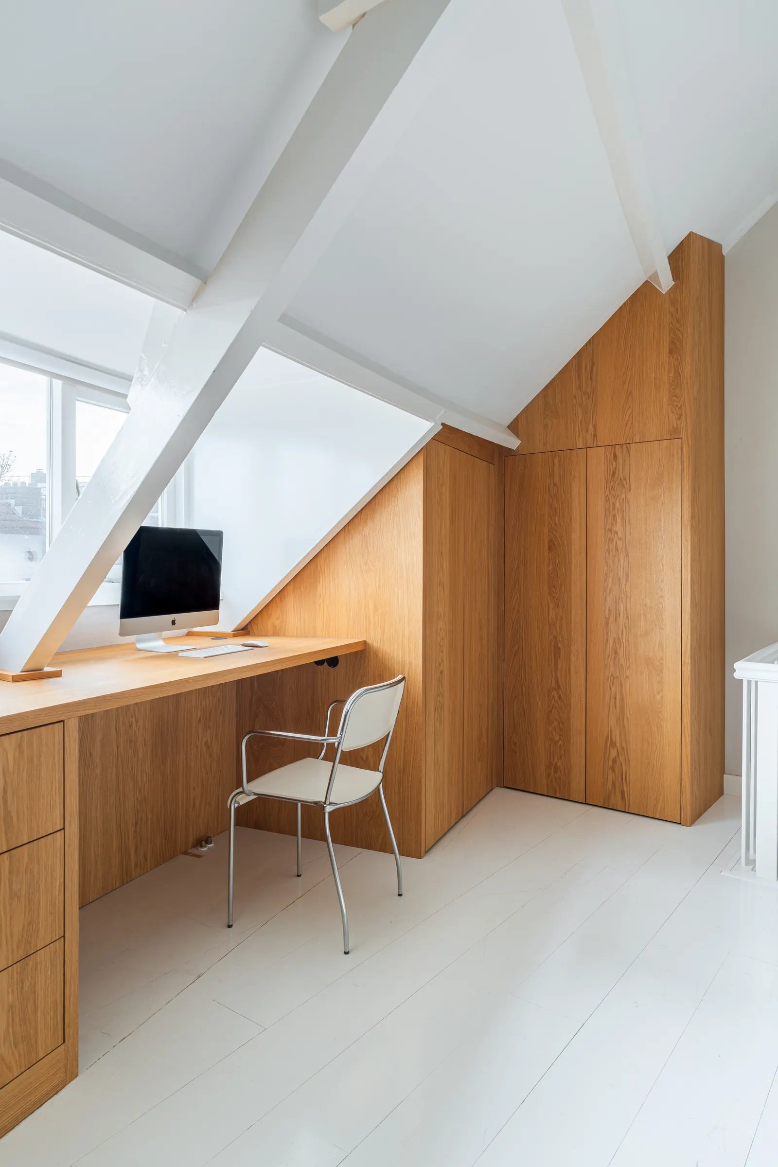 Houten bureau en maatwerkkast onder een schuine kap
